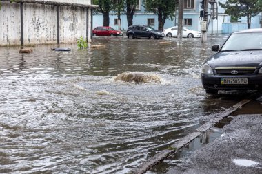 Odessa, Ukrayna - 28 Mayıs 2020: sel baskınları sırasında sel basmış yolda araba kullanmak. Arabalar suda yüzer, sokakları su basar. Arabanın üzerine su sıçradı. Büyük su birikintileriyle dolu şehir yolu.