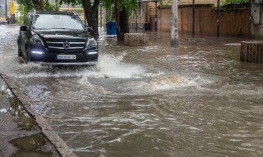 Odessa, Ukrayna - 28 Mayıs 2020: sel baskınları sırasında sel basmış yolda araba kullanmak. Arabalar suda yüzer, sokakları su basar. Arabanın üzerine su sıçradı. Büyük su birikintileriyle dolu şehir yolu.