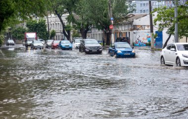 Odessa, Ukrayna - 28 Mayıs 2020: sel baskınları sırasında sel basmış yolda araba kullanmak. Arabalar suda yüzer, sokakları su basar. Arabanın üzerine su sıçradı. Büyük su birikintileriyle dolu şehir yolu.