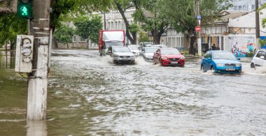 Odessa, Ukrayna - 28 Mayıs 2020: sel baskınları sırasında sel basmış yolda araba kullanmak. Arabalar suda yüzer, sokakları su basar. Arabanın üzerine su sıçradı. Büyük su birikintileriyle dolu şehir yolu.