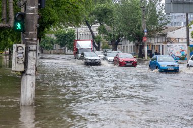 Odessa, Ukrayna - 28 Mayıs 2020: sel baskınları sırasında sel basmış yolda araba kullanmak. Arabalar suda yüzer, sokakları su basar. Arabanın üzerine su sıçradı. Büyük su birikintileriyle dolu şehir yolu.