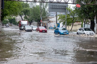 Odessa, Ukrayna - 28 Mayıs 2020: sel baskınları sırasında sel basmış yolda araba kullanmak. Arabalar suda yüzer, sokakları su basar. Arabanın üzerine su sıçradı. Büyük su birikintileriyle dolu şehir yolu.