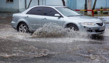 Odessa, Ukrayna - 28 Mayıs 2020: sel baskınları sırasında sel basmış yolda araba kullanmak. Arabalar suda yüzer, sokakları su basar. Arabanın üzerine su sıçradı. Büyük su birikintileriyle dolu şehir yolu.