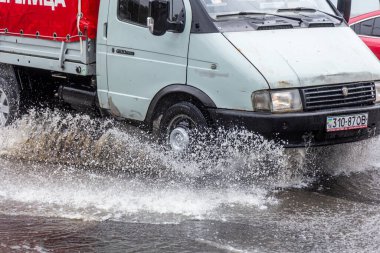 Odessa, Ukrayna - 28 Mayıs 2020: sel baskınları sırasında sel basmış yolda araba kullanmak. Arabalar suda yüzer, sokakları su basar. Arabanın üzerine su sıçradı. Büyük su birikintileriyle dolu şehir yolu.