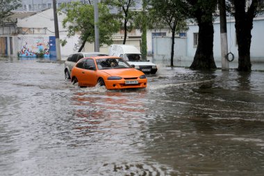 Odessa, Ukrayna - 28 Mayıs 2020: sel baskınları sırasında sel basmış yolda araba kullanmak. Arabalar suda yüzer, sokakları su basar. Arabanın üzerine su sıçradı. Büyük su birikintileriyle dolu şehir yolu.