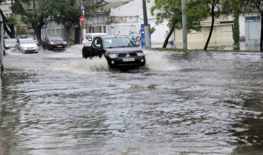 Odessa, Ukrayna - 28 Mayıs 2020: sel baskınları sırasında sel basmış yolda araba kullanmak. Arabalar suda yüzer, sokakları su basar. Arabanın üzerine su sıçradı. Büyük su birikintileriyle dolu şehir yolu.