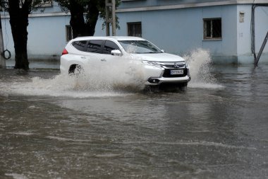 Odessa, Ukrayna - 28 Mayıs 2020: sel baskınları sırasında sel basmış yolda araba kullanmak. Arabalar suda yüzer, sokakları su basar. Arabanın üzerine su sıçradı. Büyük su birikintileriyle dolu şehir yolu.
