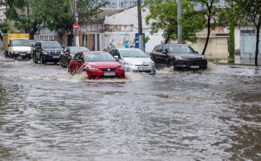 Odessa, Ukrayna - 28 Mayıs 2020: sel baskınları sırasında sel basmış yolda araba kullanmak. Arabalar suda yüzer, sokakları su basar. Arabanın üzerine su sıçradı. Büyük su birikintileriyle dolu şehir yolu.