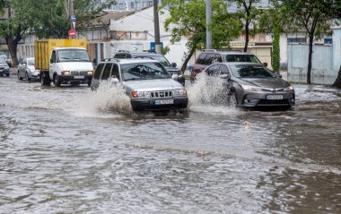 Odessa, Ukrayna - 28 Mayıs 2020: sel baskınları sırasında sel basmış yolda araba kullanmak. Arabalar suda yüzer, sokakları su basar. Arabanın üzerine su sıçradı. Büyük su birikintileriyle dolu şehir yolu.