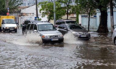 Odessa, Ukrayna - 28 Mayıs 2020: sel baskınları sırasında sel basmış yolda araba kullanmak. Arabalar suda yüzer, sokakları su basar. Arabanın üzerine su sıçradı. Büyük su birikintileriyle dolu şehir yolu.