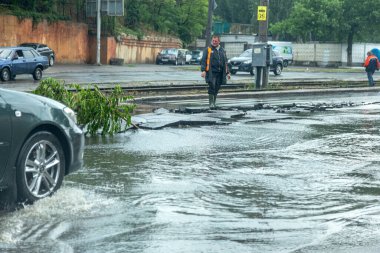 Odessa, Ukrayna - 28 Mayıs 2020: sel baskınları sırasında sel basmış yolda araba kullanmak. Arabalar suda yüzer, sokakları su basar. Arabanın üzerine su sıçradı. Büyük su birikintileriyle dolu şehir yolu.