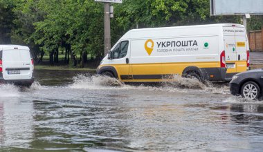 Odessa, Ukrayna - 28 Mayıs 2020: sel baskınları sırasında sel basmış yolda araba kullanmak. Arabalar suda yüzer, sokakları su basar. Arabanın üzerine su sıçradı. Büyük su birikintileriyle dolu şehir yolu.