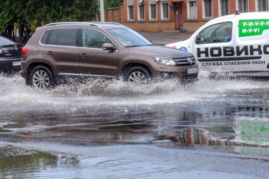 Odessa, Ukrayna - 28 Mayıs 2020: sel baskınları sırasında sel basmış yolda araba kullanmak. Arabalar suda yüzer, sokakları su basar. Arabanın üzerine su sıçradı. Büyük su birikintileriyle dolu şehir yolu.