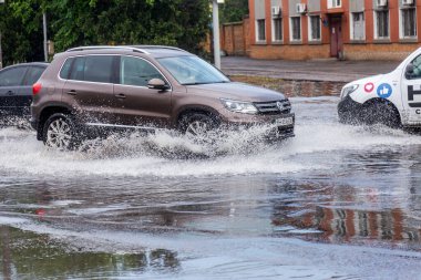 Odessa, Ukrayna - 28 Mayıs 2020: sel baskınları sırasında sel basmış yolda araba kullanmak. Arabalar suda yüzer, sokakları su basar. Arabanın üzerine su sıçradı. Büyük su birikintileriyle dolu şehir yolu.