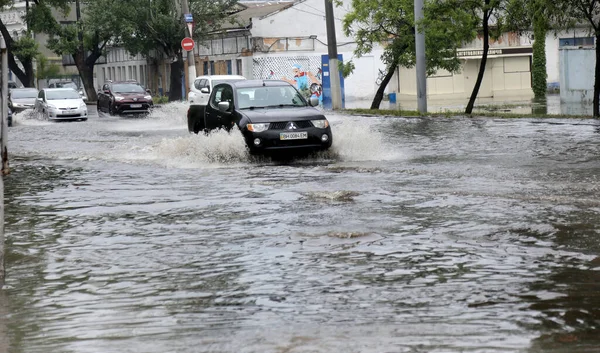 Odessa, Ukrayna - 28 Mayıs 2020: sel baskınları sırasında sel basmış yolda araba kullanmak. Arabalar suda yüzer, sokakları su basar. Arabanın üzerine su sıçradı. Büyük su birikintileriyle dolu şehir yolu.