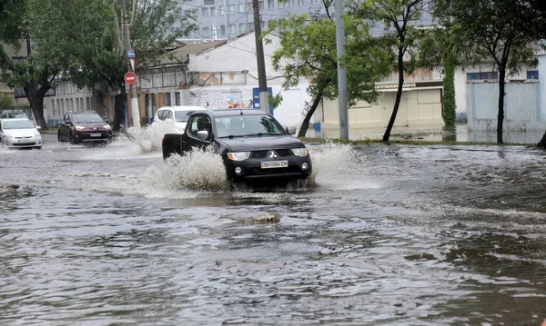 Odessa, Ukrayna - 28 Mayıs 2020: sel baskınları sırasında sel basmış yolda araba kullanmak. Arabalar suda yüzer, sokakları su basar. Arabanın üzerine su sıçradı. Büyük su birikintileriyle dolu şehir yolu.