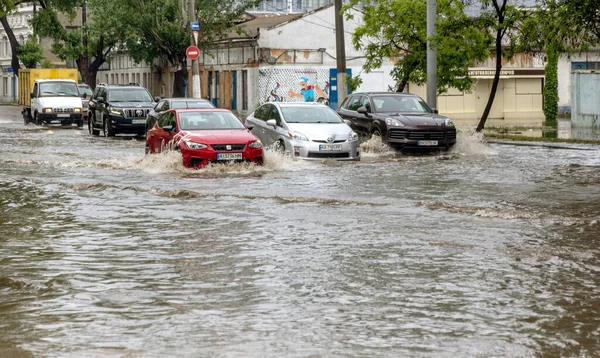 Odessa, Ukrayna - 28 Mayıs 2020: sel baskınları sırasında sel basmış yolda araba kullanmak. Arabalar suda yüzer, sokakları su basar. Arabanın üzerine su sıçradı. Büyük su birikintileriyle dolu şehir yolu.
