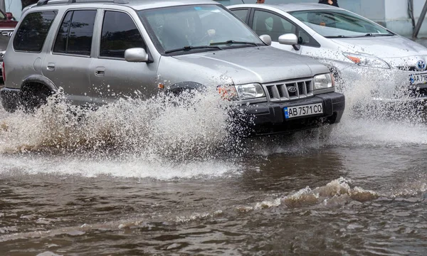Odessa, Ukrayna - 28 Mayıs 2020: sel baskınları sırasında sel basmış yolda araba kullanmak. Arabalar suda yüzer, sokakları su basar. Arabanın üzerine su sıçradı. Büyük su birikintileriyle dolu şehir yolu.