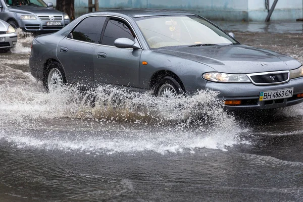 stock image Odessa, Ukraine - May 28, 2020: driving car on flooded road during flood caused by torrential rains. Cars float on water, flooding streets. Splash on car. Flooded city road with large puddle