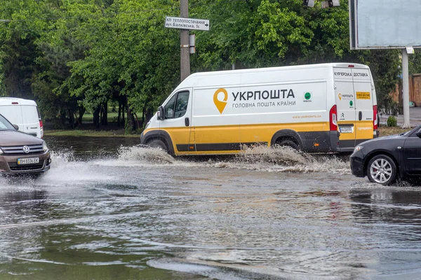 Odessa, Ukrayna - 28 Mayıs 2020: sel baskınları sırasında sel basmış yolda araba kullanmak. Arabalar suda yüzer, sokakları su basar. Arabanın üzerine su sıçradı. Büyük su birikintileriyle dolu şehir yolu.