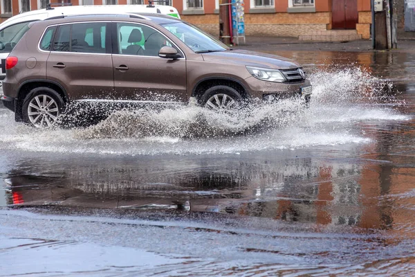 Odessa, Ukrayna - 28 Mayıs 2020: sel baskınları sırasında sel basmış yolda araba kullanmak. Arabalar suda yüzer, sokakları su basar. Arabanın üzerine su sıçradı. Büyük su birikintileriyle dolu şehir yolu.