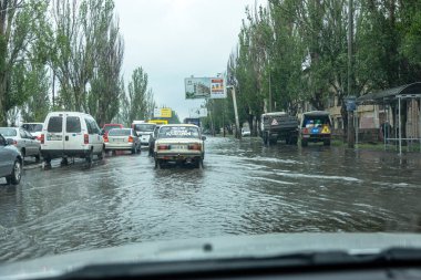 Odessa, Ukrayna - 28 Mayıs 2020: sel baskınları sırasında sel basmış yolda araba kullanmak. Arabalar suda yüzer, sokakları su basar. Arabanın üzerine su sıçradı. Büyük su birikintileriyle dolu şehir yolu.