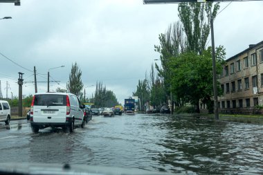 Odessa, Ukrayna - 28 Mayıs 2020: sel baskınları sırasında sel basmış yolda araba kullanmak. Arabalar suda yüzer, sokakları su basar. Arabanın üzerine su sıçradı. Büyük su birikintileriyle dolu şehir yolu.