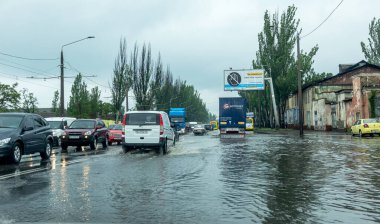Odessa, Ukrayna - 28 Mayıs 2020: sel baskınları sırasında sel basmış yolda araba kullanmak. Arabalar suda yüzer, sokakları su basar. Arabanın üzerine su sıçradı. Büyük su birikintileriyle dolu şehir yolu.