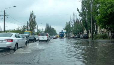 Odessa, Ukrayna - 28 Mayıs 2020: sel baskınları sırasında sel basmış yolda araba kullanmak. Arabalar suda yüzer, sokakları su basar. Arabanın üzerine su sıçradı. Büyük su birikintileriyle dolu şehir yolu.