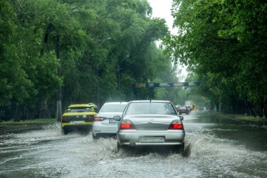 Odessa, Ukrayna - 28 Mayıs 2020: sel baskınları sırasında sel basmış yolda araba kullanmak. Arabalar suda yüzer, sokakları su basar. Arabanın üzerine su sıçradı. Büyük su birikintileriyle dolu şehir yolu.