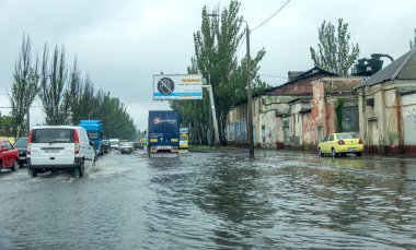 Odessa, Ukrayna - 28 Mayıs 2020: sel baskınları sırasında sel basmış yolda araba kullanmak. Arabalar suda yüzer, sokakları su basar. Arabanın üzerine su sıçradı. Büyük su birikintileriyle dolu şehir yolu.