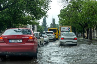 Odessa, Ukrayna - 28 Mayıs 2020: sel baskınları sırasında sel basmış yolda araba kullanmak. Arabalar suda yüzer, sokakları su basar. Arabanın üzerine su sıçradı. Büyük su birikintileriyle dolu şehir yolu.