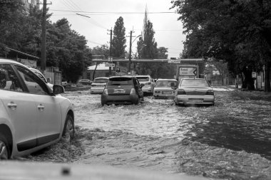 Odessa, Ukrayna - 28 Mayıs 2020: sel baskınları sırasında sel basmış yolda araba kullanmak. Arabalar suda yüzer, sokakları su basar. Arabanın üzerine su sıçradı. Büyük su birikintileriyle dolu şehir yolu.