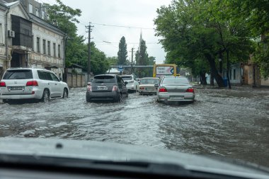 Odessa, Ukrayna - 28 Mayıs 2020: sel baskınları sırasında sel basmış yolda araba kullanmak. Arabalar suda yüzer, sokakları su basar. Arabanın üzerine su sıçradı. Büyük su birikintileriyle dolu şehir yolu.