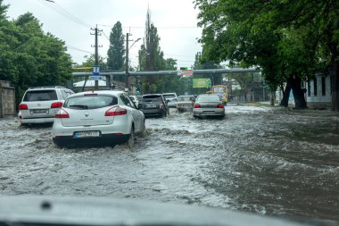 Odessa, Ukrayna - 28 Mayıs 2020: sel baskınları sırasında sel basmış yolda araba kullanmak. Arabalar suda yüzer, sokakları su basar. Arabanın üzerine su sıçradı. Büyük su birikintileriyle dolu şehir yolu.