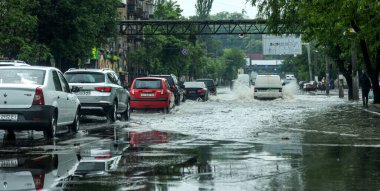Odessa, Ukrayna - 28 Mayıs 2020: sel baskınları sırasında sel basmış yolda araba kullanmak. Arabalar suda yüzer, sokakları su basar. Arabanın üzerine su sıçradı. Büyük su birikintileriyle dolu şehir yolu.