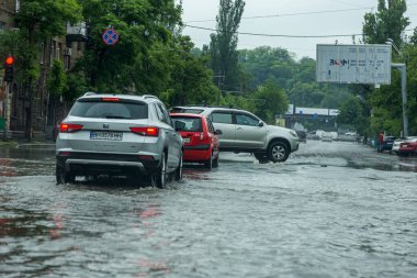 Odessa, Ukrayna - 28 Mayıs 2020: sel baskınları sırasında sel basmış yolda araba kullanmak. Arabalar suda yüzer, sokakları su basar. Arabanın üzerine su sıçradı. Büyük su birikintileriyle dolu şehir yolu.
