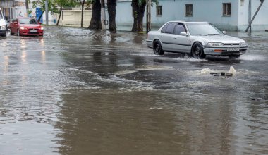 Odessa, Ukrayna - 28 Mayıs 2020: sel baskınları sırasında sel basmış yolda araba kullanmak. Arabalar suda yüzer, sokakları su basar. Arabanın üzerine su sıçradı. Büyük su birikintileriyle dolu şehir yolu.