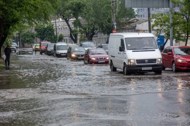 Odessa, Ukrayna - 28 Mayıs 2020: sel baskınları sırasında sel basmış yolda araba kullanmak. Arabalar suda yüzer, sokakları su basar. Arabanın üzerine su sıçradı. Büyük su birikintileriyle dolu şehir yolu.