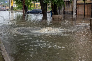 Odessa, Ukrayna - 28 Mayıs 2020: sel baskınları sırasında sel basmış yolda araba kullanmak. Arabalar suda yüzer, sokakları su basar. Arabanın üzerine su sıçradı. Büyük su birikintileriyle dolu şehir yolu.
