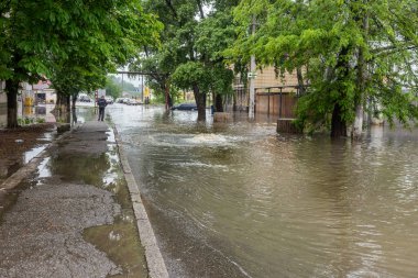 Odessa, Ukrayna - 28 Mayıs 2020: sel baskınları sırasında sel basmış yolda araba kullanmak. Arabalar suda yüzer, sokakları su basar. Arabanın üzerine su sıçradı. Büyük su birikintileriyle dolu şehir yolu.