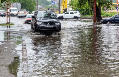 Odessa, Ukrayna - 28 Mayıs 2020: sel baskınları sırasında sel basmış yolda araba kullanmak. Arabalar suda yüzer, sokakları su basar. Arabanın üzerine su sıçradı. Büyük su birikintileriyle dolu şehir yolu.