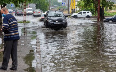 Odessa, Ukrayna - 28 Mayıs 2020: sel baskınları sırasında sel basmış yolda araba kullanmak. Arabalar suda yüzer, sokakları su basar. Arabanın üzerine su sıçradı. Büyük su birikintileriyle dolu şehir yolu.