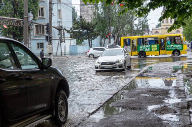 Odessa, Ukrayna - 28 Mayıs 2020: sel baskınları sırasında sel basmış yolda araba kullanmak. Arabalar suda yüzer, sokakları su basar. Arabanın üzerine su sıçradı. Büyük su birikintileriyle dolu şehir yolu.