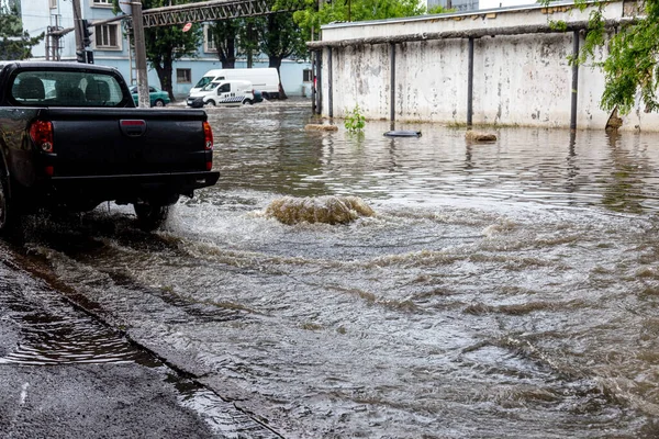 Şiddetli yağmurların yol açtığı sel baskını sırasında sel basmış yolda bir araba. Arabalar suda yüzer, sokakları su basar. Arabanın üzerine su sıçradı. Büyük su birikintileriyle dolu şehir yolu. Şehirde sağanak yağış ardından sel