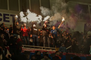 ODESSA, UKRAINE -2 Mart 2019: Shakhtar (Donetsk) maçı sırasında stadyumun tribünlerinde taraftarlar toplandı. Stadyumdaki izleyiciler. Fayer, stadyumun ışıkları yanıyor.