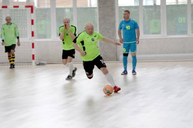 Odessa, Ukrayna - 29 Mayıs 2020: 50 + gaziler arasında futsal kupa play-off maçı. Futsal, spor salonunun büyük sahnesinde, modern oyun alanını kapsıyor. Koridorda yoğun bir mini futbol maçı var. Parke üzerinde