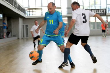 Odessa, Ukrayna - 29 Mayıs 2020: 50 + gaziler arasında futsal kupa play-off maçı. Futsal, spor salonunun büyük sahnesinde, modern oyun alanını kapsıyor. Koridorda yoğun bir mini futbol maçı var. Parke üzerinde