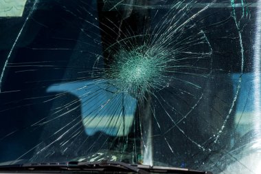 Kırık araba ön camı. Radyal çatlaklar ağı, üçlü ön cam çatlağı. Kırık bir ön cam, yolda bir taş izi olan hasarlı camlar ya da yolda düşmüş bir yaya ya da hayvan izi.