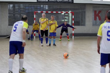 Odessa, Ukrayna - 29 Mayıs 2020: 50 + gaziler arasında futsal kupa play-off maçı. Futsal, spor salonunun büyük sahnesinde, modern oyun alanını kapsıyor. Koridorda yoğun bir mini futbol maçı var. Parke üzerinde